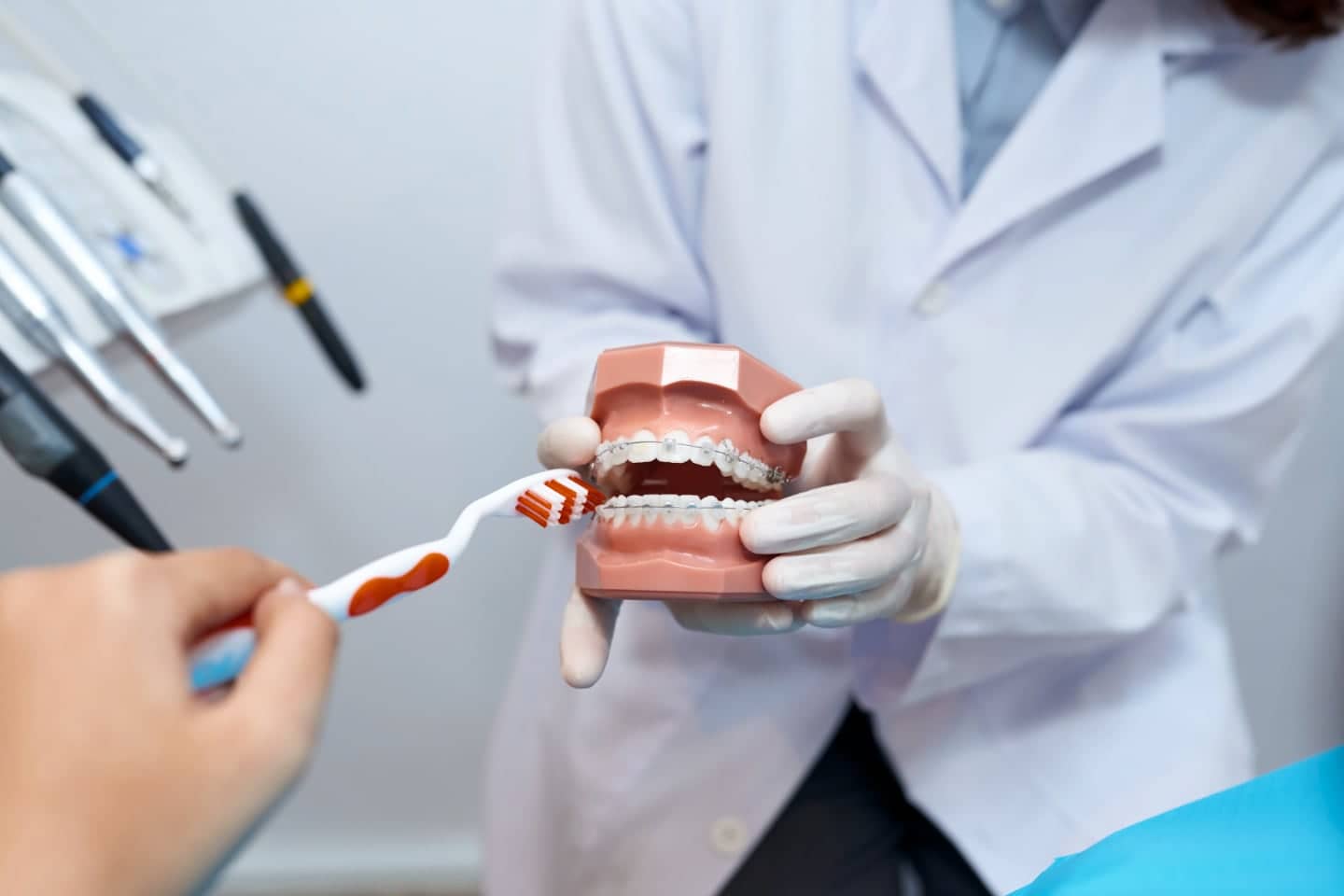 A doctor showing dental braces to a patient and how to clean them. Visit Dr Arshad's Dental Clinic in Karachi for a quick consult!